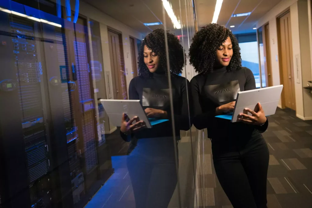 IT professional using a tablet to monitor server room technology systems.