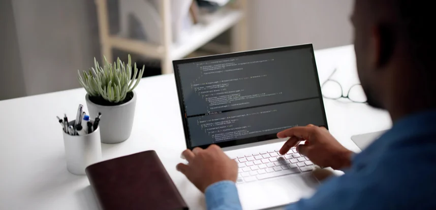 IT professional working on programming code on a laptop.